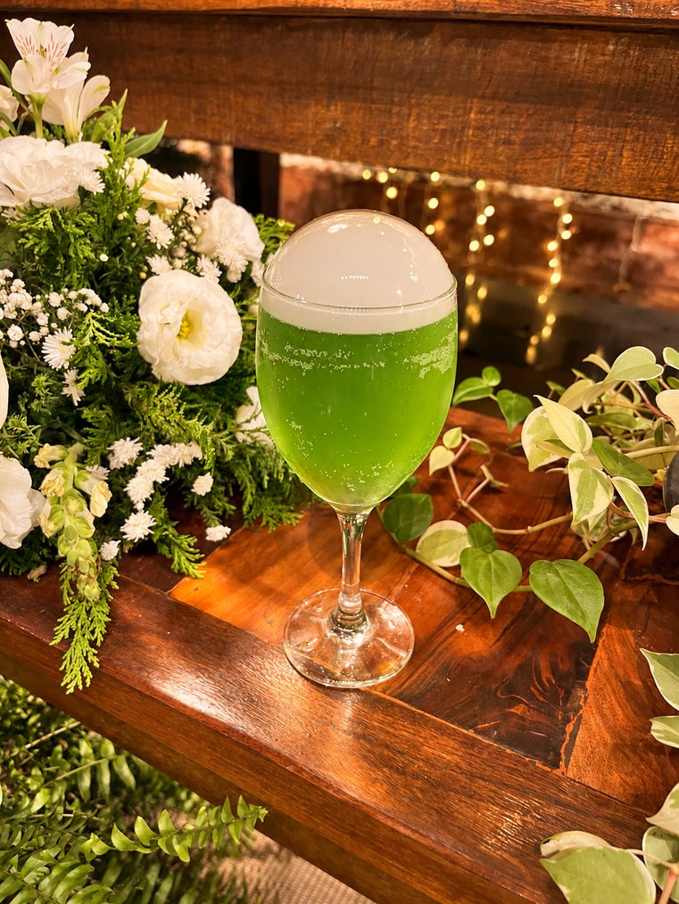 Drink verde com espuma entre flores brancas