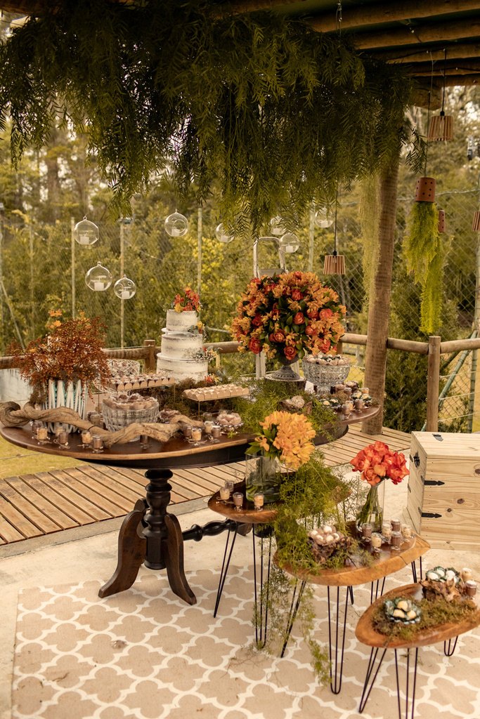 Mesa de doces sob a pérgola decorada com plantas suspensas