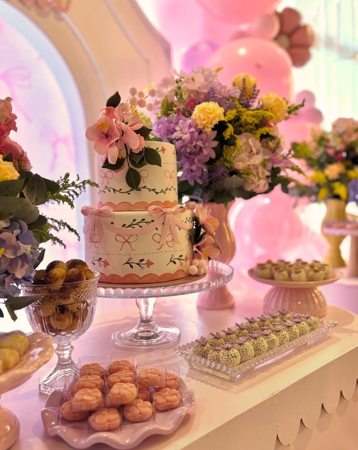 Bolo decorado com flores e mesa de doces em tom rosado