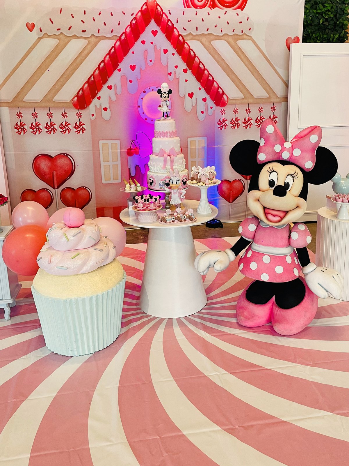 Cenário em tons de rosa e vermelho com cupcake gigante e Minnie