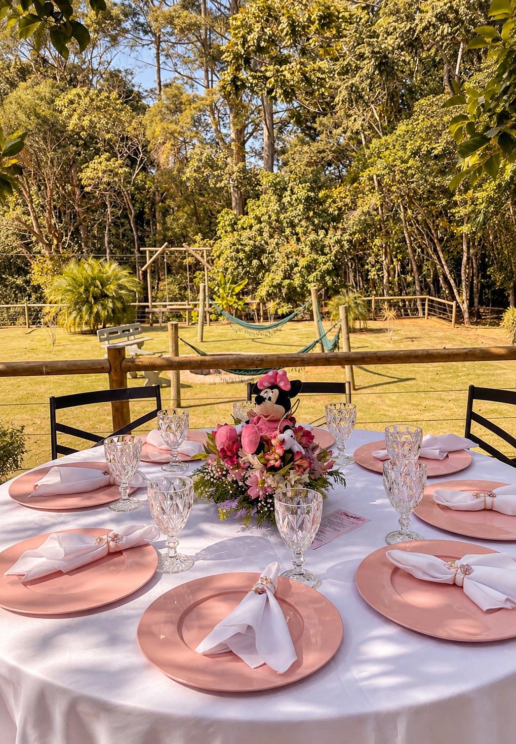 Mesa dos convidados com sousplat rosa e arranjo de flores